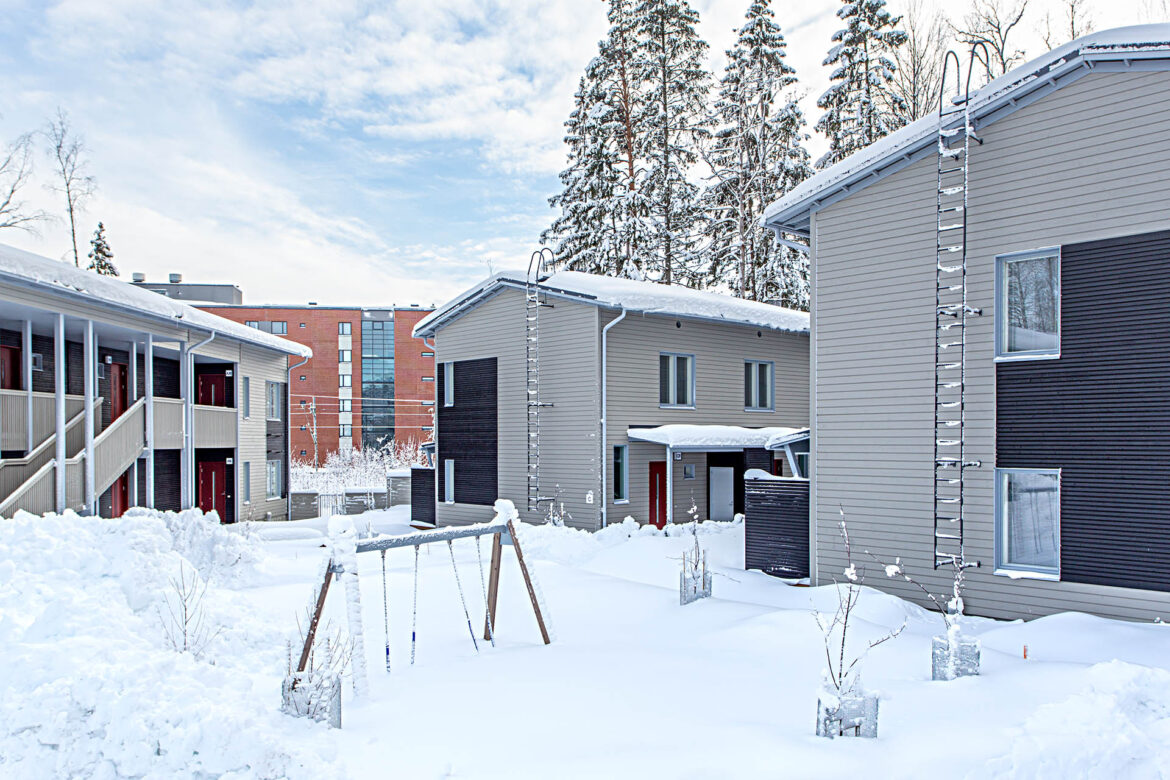 Talvinen näkymä rakennuksien ohessa olevasta leikkikentästä